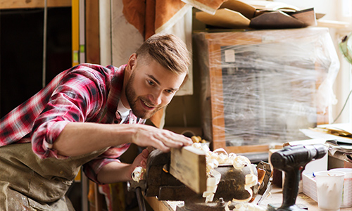 Man woodworking with a hand plane in a workshop.